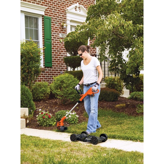 20 volt max lithium 12 inch 3 in 1 compact mower being used by a person.