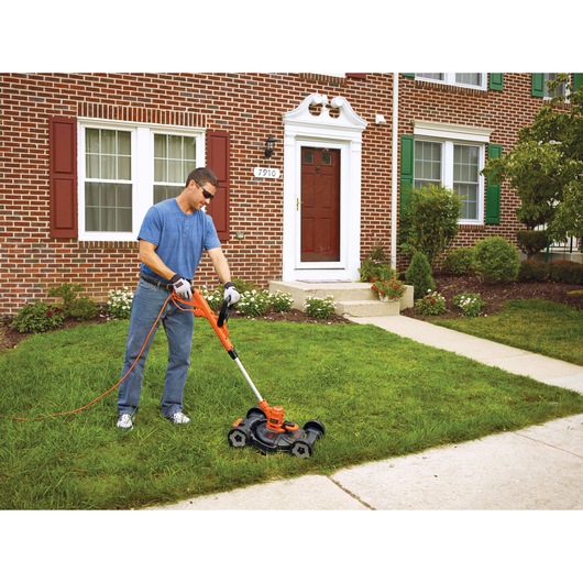 6.5 Ampere 12 inch electric 3 in 1 compact mower being used by a person to mow the lawn.