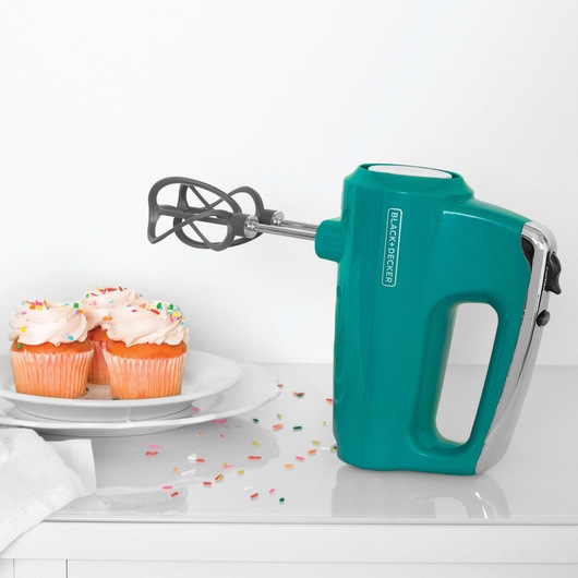 Helix performance premium hand mixer placed next to two decorated cupcakes.