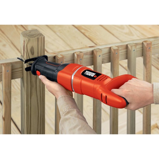 Black and decker saber saw being used by a person to cut through wood.